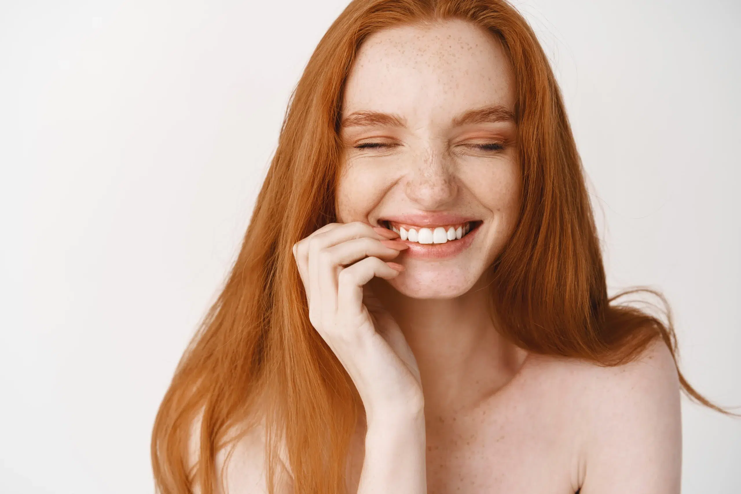 close up happy redhead woman with pale no makeup skin perfect smile laughing looking joyful standing naked white wall scaled